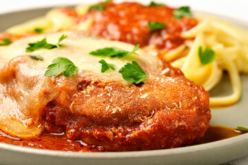 Plate of chicken parmigiano with pasta close-up