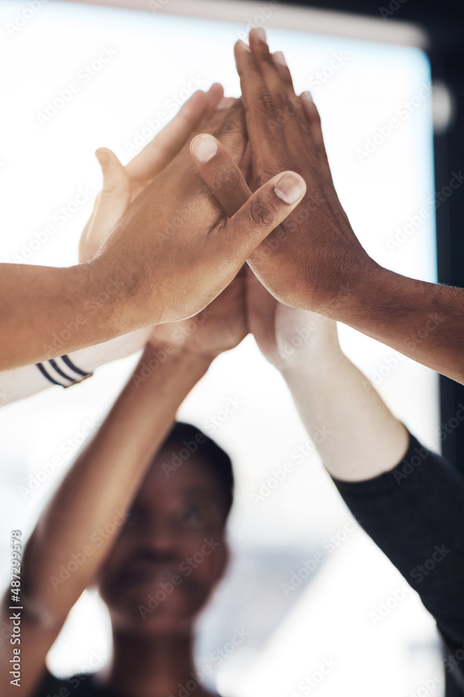 Poster Time to unify. Cropped shot of a group of colleagues giving each other a high five at work.