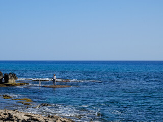 fisherman catches fish on the rocky seashore