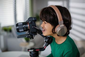 Happy multiracial boy cameraman amateur with headphones at home.