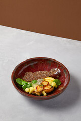 Roasted sea scallops with celery mash and zucchini balls on dark handmade ceramic dish. Seafood dish in modern serveware on gray concrete background. Inspirational chef.