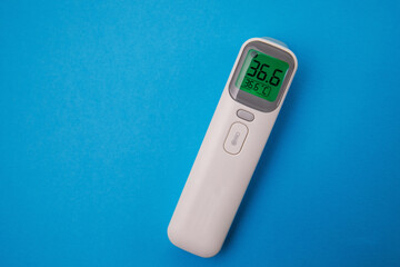 Non-contact infrared thermometer isolated on blue background. Thermometer Isometric medical digital non-contact infrared sight. Hand reading forehead. Temperature measuring device.