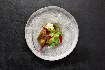 Zucchini fritters with fish ceviche and cheese cream. Healthy food - vegetables fritters and fish tartar. Inspirational chefs food on dark background. Modern food. Contemporary menu for restaurant.
