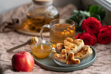 composition with a glass teapot and a glass mug with sea buckthorn tea and cakes