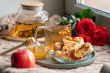 composition with a glass teapot and a glass mug with sea buckthorn tea and cakes