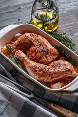 raw turkey chicken thighs rubbed with spices and salt, on a baking sheet, with oranges lemons garlic rosemary thyme and olive oil. the concept of a healthy and tasty dinner for two.