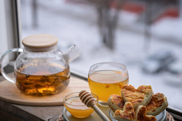 composition with a glass teapot and glass cup filled with tea and cake on the plate