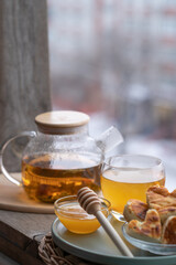 composition with a glass teapot and glass cup filled with tea and cake on the plate
