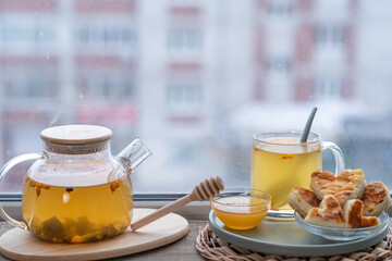 composition with a glass teapot and glass cup filled with tea and cake on the plate