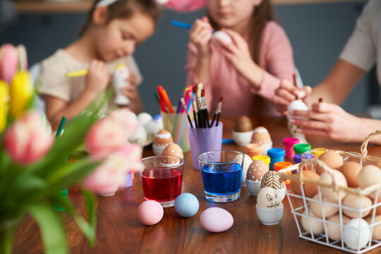 Detail of caucasian family of four decorates easter eggs at home