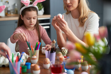 Happy caucasian family of four people decorates easter eggs at home