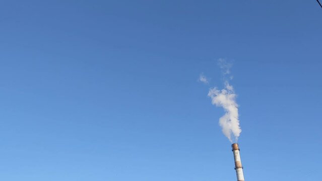 Against the background of the blue sky, smoke comes out of the chimney