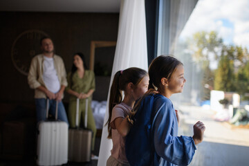 Happy young family with two children and luggage in room at luxury hotel, summer holiday.