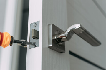 Repairing the door lock in the room using a screwdriver. The concept repair yourself. Close-up. Selective focus. © D-point