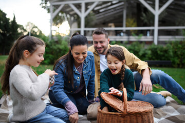 Happy young family sitting on blanket and having take away picnic outdoors in restaurant area.