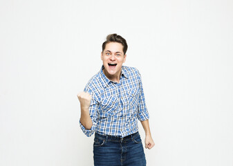 Fototapeta premium Portrait of a young cheerful excited man wearing blue plaid shirt. celebrating success