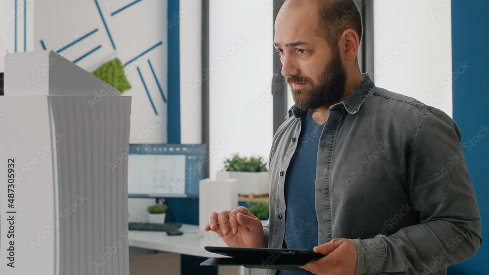 Poster close up of man architect using digital tablet to design building model and layout in office. expert