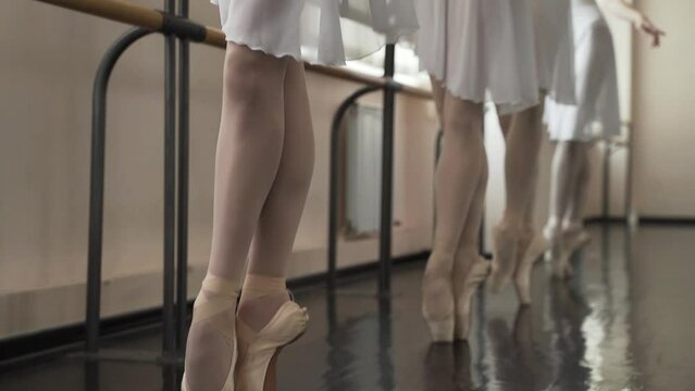 Young slender ballerinas are engaged in the dance hall. Girls in white tights and punts dancing ballet