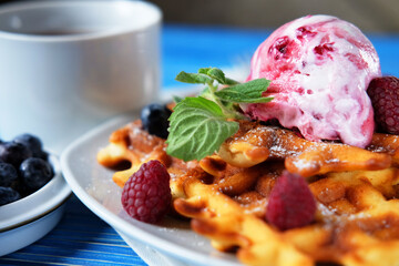 Belgian waffles with fresh berries and ice cream over blue wooden background