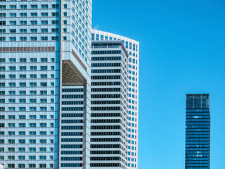 Plakat front view on modern white skyscrapers over blue sky background