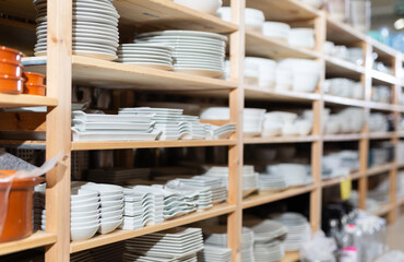 Showcase with various new plates stacked on shelves in dishware department of supermarket