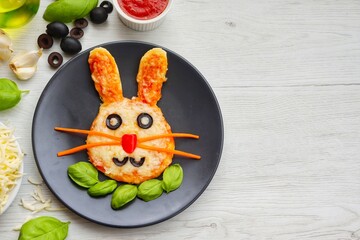 Mini easter bunny pizza on plate with white wood background.Art food idea for kids Easter's party.Top view.Copy space