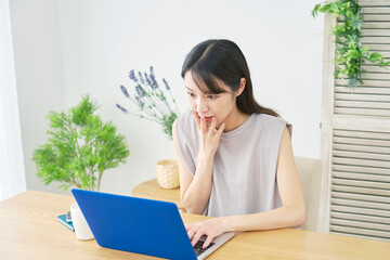 女性　パソコンを見て驚く　リビング