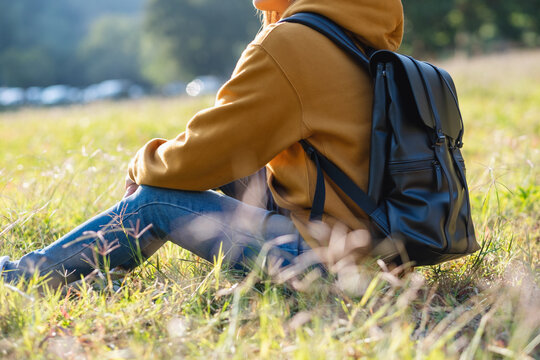 Closeup image of a female traveler with backpack sitting in the park