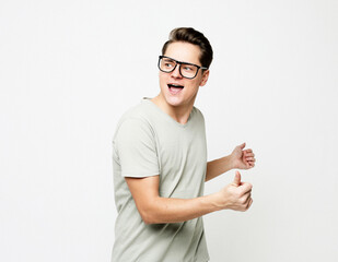 Happy young handsome man wearing eyeglasses gesturing and keeping mouth open while standing against white background