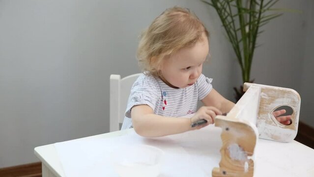 small child paints a wooden crib toy. Development and education of children