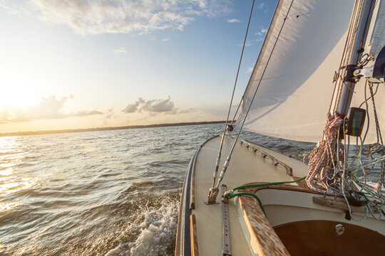 Sailing Boat Sailing Fast Into The Sunset On Choppy Sea With Slightly Tilted Horizon