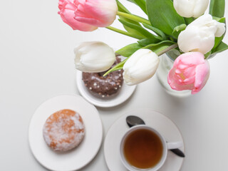 Fototapeta na wymiar donuts, a cup of coffee, and tulips on top. Concept, breakfast and spring, holidays, spring holiday.