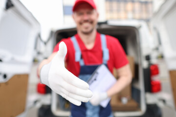 A courier in a red uniform holds out his hand in a white glove