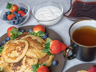 Sweet homemade pancakes with blueberries and strawberries jam and sour cream. tea on a white background, view from the top. The concept of breakfast, snacks and nutrition. Maslenitsa.