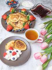 Sweet homemade pancakes with blueberries and strawberries jam and sour cream. tea on a white background, view from the top. The concept of breakfast, snacks and nutrition. Maslenitsa.