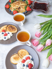 Sweet homemade pancakes with blueberries and strawberries jam and sour cream. tea on a white background, view from the top. The concept of breakfast, snacks and nutrition. Maslenitsa.