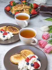 Sweet homemade pancakes with blueberries and strawberries jam and sour cream. tea on a white background, view from the top. The concept of breakfast, snacks and nutrition. Maslenitsa.