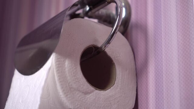 Close-up of female hands that place a roll of toilet paper in a holder in the toilet. It's rusty and old. The concept of personal hygiene.