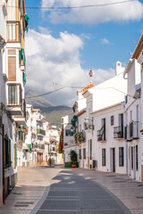 Beautiful streets of Nerja. Typically Andalusian houses. Small streets with white houses and flower pots in balcony. Touristic travel destination on Costa del Sola - Malaga. Sunny winter days