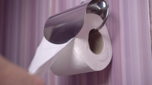 Close-up of female hands that place a roll of toilet paper in a holder in the toilet. It's rusty and old. The concept of personal hygiene.