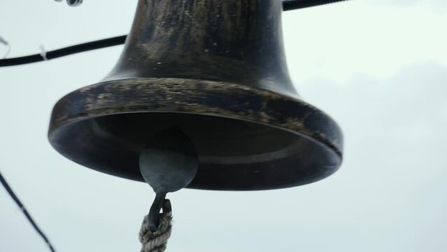 The ringer pulls the rope of a bronze bell.