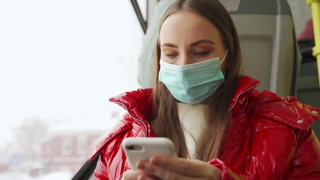 Woman Passenger With Protective Mask Types Message In Smartphone Tiding Tram. Young Employee On Way To Work In Urban Public Transport At Quarantine Closeup