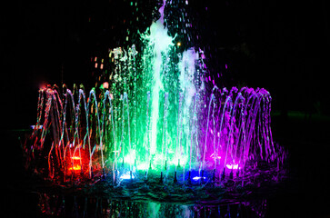 A glowing multicolored musical water fountain at night. Colorful light