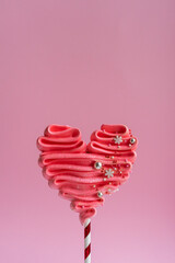 Pink meringue heart on a stick. Pink background, sweets for lovers. Meringue handmade.