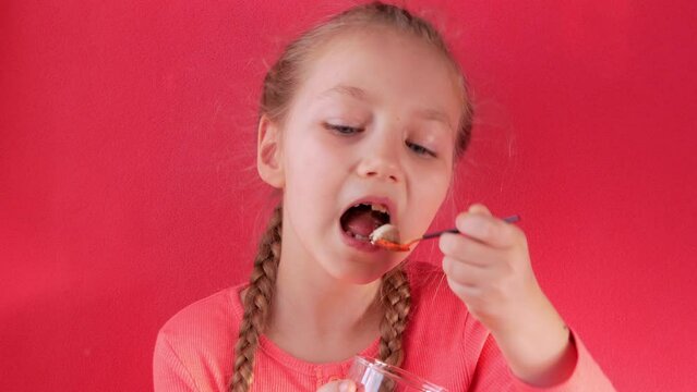 Child eating yogurt jelly pink background. Dairy product diet Lactobacillus Acidophilus, healthy homemade breakfast menu. Kids healthcare. Vegan food nut milk gelatin non-dairy dessert Protein pudding