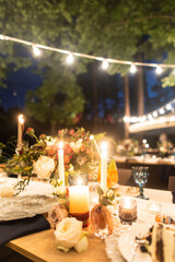 night wedding ceremony, the arch is decorated with flowers, candles and garlands of light bulbs and there is a wedding cake on the table