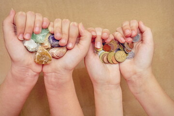 Semiprecious fossil stones and coins of different countries on the palms of the girls