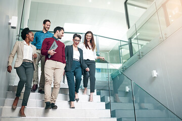 The end of another successful business day. Shot of a group of colleagues talking together while walking down stairs in a large modern office. - obrazy, fototapety, plakaty
