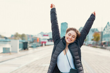 Young happy woman with her her hands raised up enjoying outdoor weather