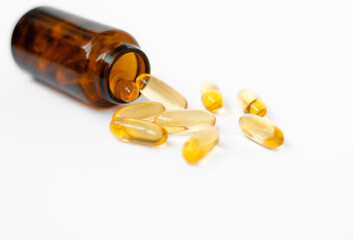 Vitamin capsules in a glass jar on a white background. Dietary supplements: fish oil, omega-3, omega-6, omega-9, vitamin A, E, vitamin D, vitamin D3, evening primrose oil, borage.